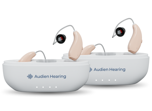 Two Audien Hearing devices with charging cases on a white background
